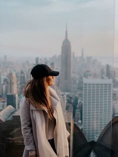 a woman standing on top of a tall building looking out at the city below her