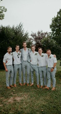 a group of men standing next to each other on top of a lush green field