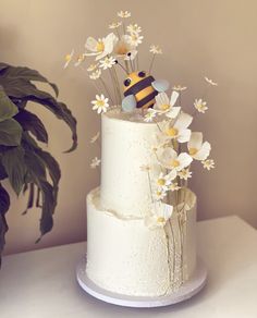 a white cake with flowers and a bee on top