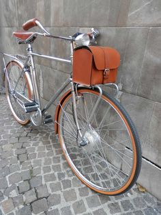 an orange and silver bicycle parked next to a wall on a cobblestone street