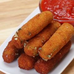 some fried food on a white plate next to a small bowl of ketchup