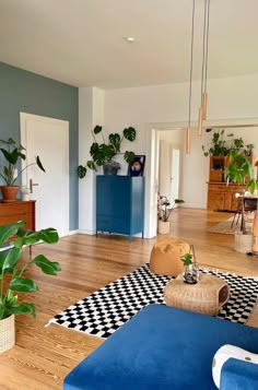 a living room with blue couches and potted plants on the floor in it