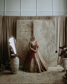 a woman standing in front of a large mirror next to a vase and flower arrangement