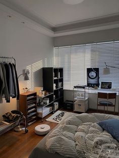 a bedroom with a bed, desk and clothes hanging on the rack in front of it