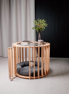 a round wooden table with a dog bed on top and a plant in the middle