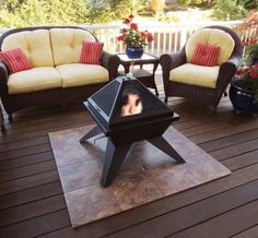 a fire pit sitting on top of a wooden deck next to two chairs and a table