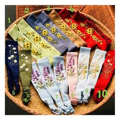 seven pairs of socks with embroidered flowers on them in a wicker basket for display