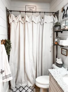 a bathroom with a white shower curtain and black and white rugs on the floor