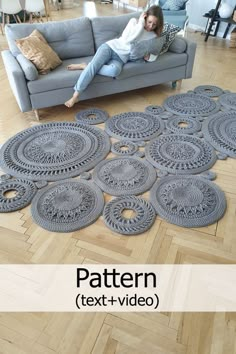 a woman sitting on top of a gray couch next to a rug with circular designs