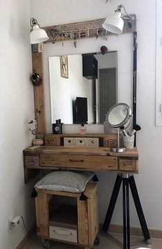 a wooden desk with a mirror and lights on top of it in front of a white wall