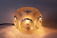 a glass ball with some lights on it sitting on a table next to a black cord