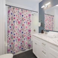 a bathroom with floral shower curtain next to a white toilet and sink in front of a mirror