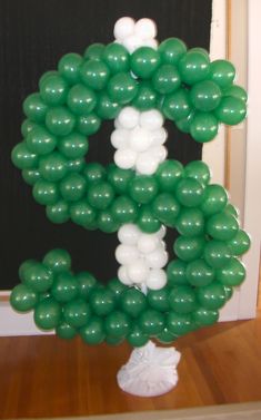 green and white balloons are arranged in the shape of the letter g on a table