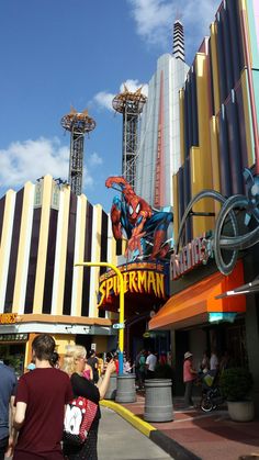 people are standing in front of the entrance to an amusement park that has spider man on it