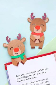 two paper reindeers are next to an open book with a poem written in it