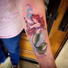 a woman's arm with a mermaid tattoo on it