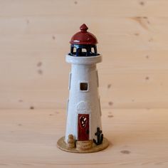 a small white and red lighthouse on a wooden table