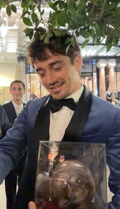 a man in a tuxedo is holding a glass case with an image on it