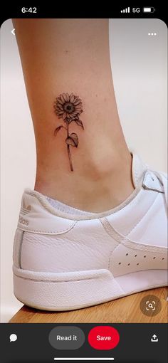 a woman's foot with a flower tattoo on the side of her ankle and behind her is a white tennis shoe