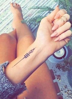 a woman's arm with a tattoo on it, sitting next to a potted plant