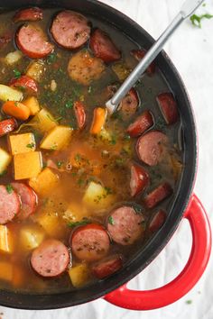 a pot filled with sausage and potatoes on top of a table