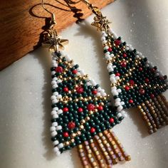 a pair of beaded christmas tree earrings sitting on top of a table