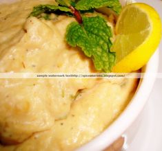 a white bowl filled with mashed potatoes and garnished with lemon wedges