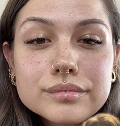 a close up of a person with piercings on her nose and nose ring, looking at the camera