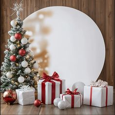 a christmas tree with presents under it in front of a large white circle and wooden wall