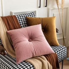 pillows on a couch in front of a white wall with black and brown checkerboard