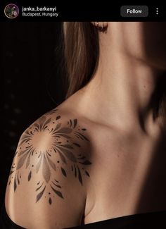 a woman with a tattoo on her shoulder is looking at the camera and has an interesting design