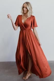 a woman in an orange dress posing for the camera with her hand on her hip