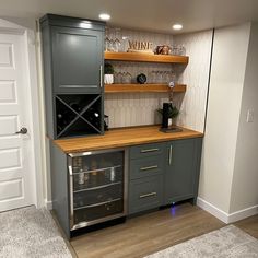 a kitchen with grey cabinets and wooden counter tops, wine glasses on the top shelf