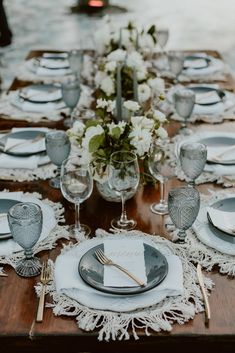 a wooden table topped with white plates and silverware