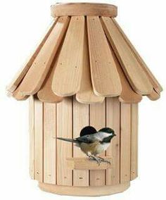 a bird is perched on the side of a wooden bird house that has a roof