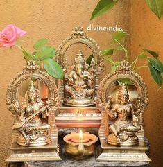 three small statues sitting on top of a table next to a pink rose