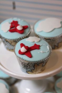 three cupcakes with blue frosting and red bows are on a white plate