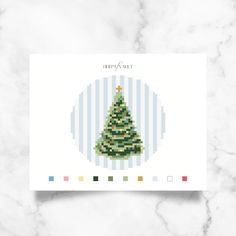 a cross stitch christmas tree card on a marble surface