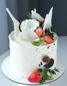 a white cake with strawberries and kiwis on top