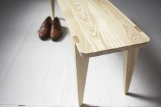 a wooden bench sitting on top of a white floor next to a pair of shoes