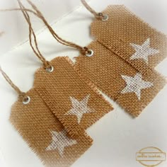 three brown tags with white stars are hanging from twine strings on top of each other