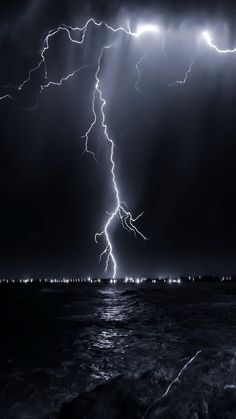 lightning striking over the ocean at night time