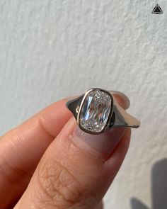 a person holding a ring with a large diamond in it's center and two fingers