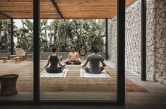 three people are sitting on the ground in yoga mats and meditating with each other