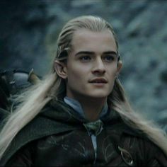 a man with long blonde hair wearing a cloak