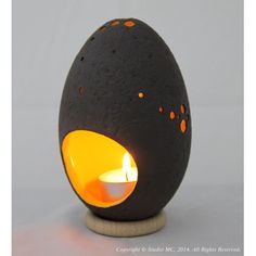 an egg shaped tea light holder with a lit candle in the center and dots on it