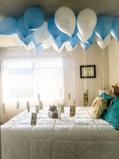 a bed with blue and white balloons hanging from it's headboard in front of a window