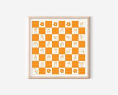 an orange and white checkerboard pattern with flowers in the middle, framed on a wall