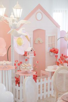 a doll house is decorated with pink and white furniture, flowers, and balloons in the background