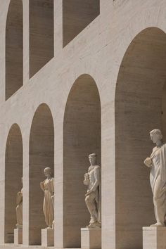 the statues are all lined up against the wall and in front of them is an arch